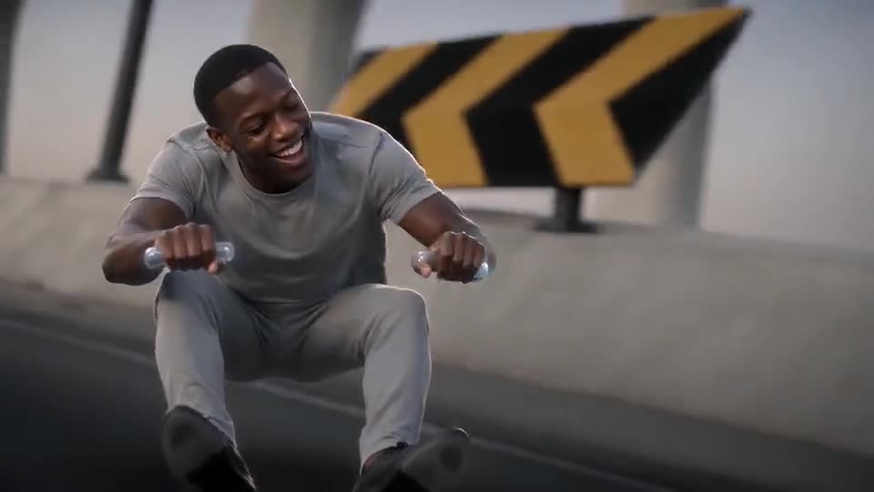 Template frame: a smiling man in a grey tee, caught mid-squat above a dusk highway, fists gripping nothing, a chevron warning board in the background